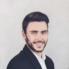 Smiling young man with a beard wearing a dark blazer and white shirt
